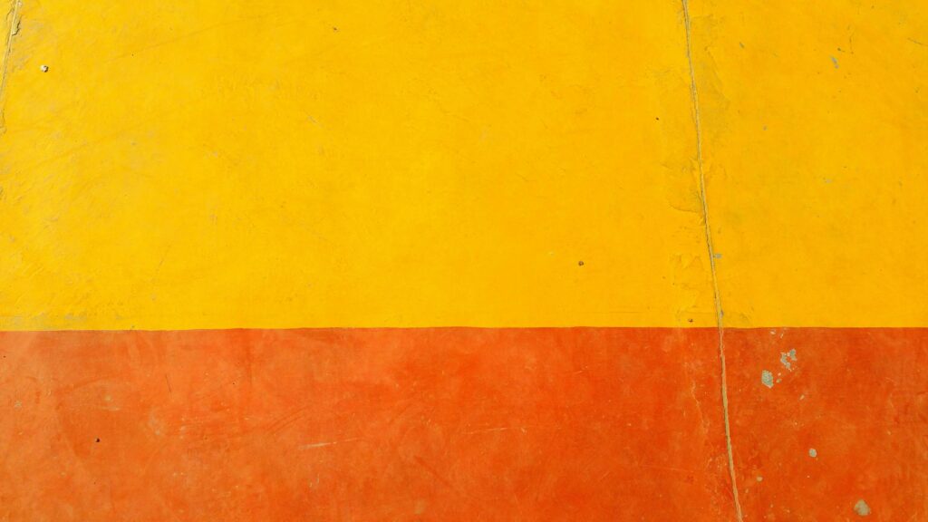 Close-up of a textured yellow and orange wall with rough surface
